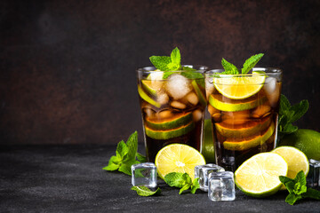 Cuba Libre alcoholic cocktail, iced drink on dark background.