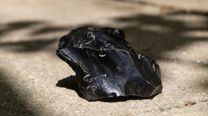 A piece of obsidian. Obsidian in sunlight. Black obsidian