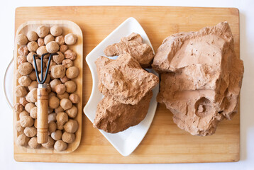 Edible caramel clay stones on a wooden plate with a small garden wrack and brown clay stones on a...