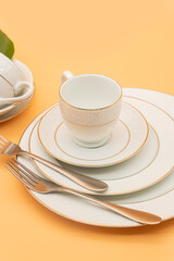 White porcelain tea cup with a golden line decoration on colour background,