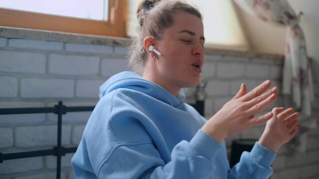 Woman in her room in a cozy clothes enjoying music on her bluetooth headphones, 4k