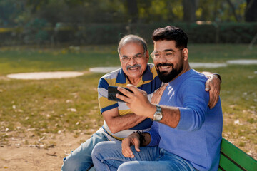 Obraz premium Young man taking selfie with his father at park