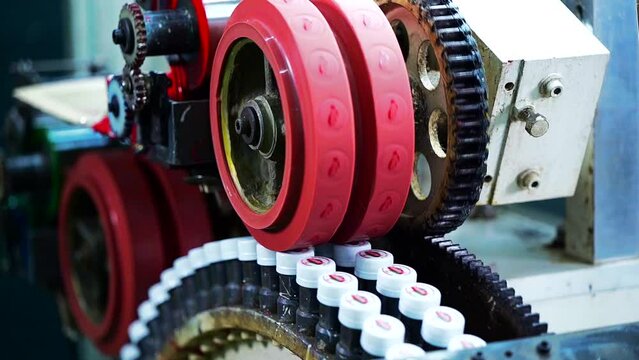 A close-up of a machine punching or stamping the logo of company on a bottle cap. Plastic bottle factory. 