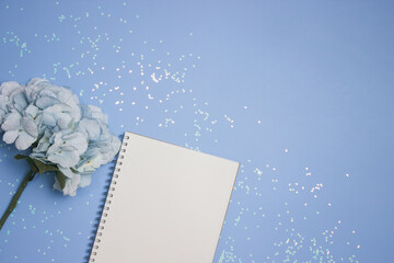 A notebook with blue flowers over the glitter blue background. 