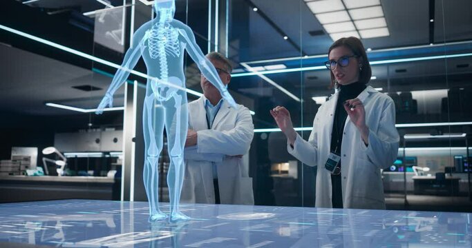Two Bioengineers Working With Computer-Powered Animated VFX Hologram Of Human Body And Organs In Futuristic Lab. Man And Woman Researching Blood Flow, Developing Innovative Healthcare Solutions.