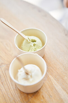 Vanilla and pistachio ice-cream. Ice cream in two disposable cups on the table. Italian gelateria. Natural fresh gelato. 