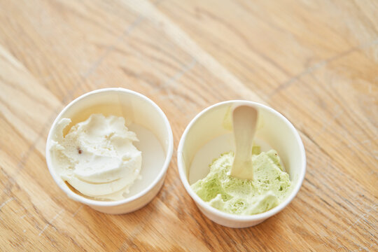 Vanilla and pistachio ice-cream. Ice cream in two disposable cups on the table. Italian gelateria. Natural fresh gelato. 
