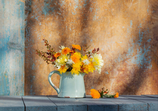 chrysanthemum flowers in jug on background old wall in sunlight