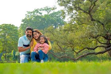 Fototapeta premium Happy indian couple with his little girl at garden.