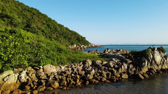 Drone shot of rocks at the bottom of a mountains bordering the sea in Brazil