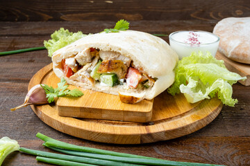 Kebab with chicken and vegetables in a pit, wood background.