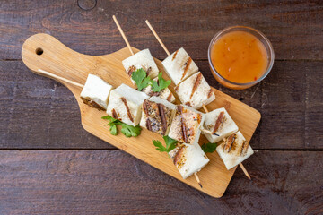Three skewers with fried cheese, skewers of paneer cheese. Vegetarian barbecue. Healthy eating. Wooden background, top view.