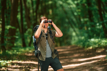 Looking through the binoculars. Tourist in summer forest. Conception of exploration and leisure