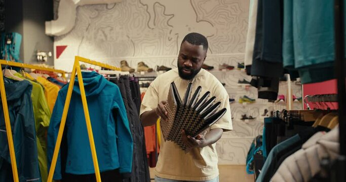 Outdoor Gear Exploration: African-American Man Inspects Interesting Brown Mat in Camping Gear Store