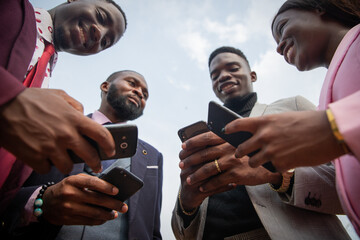 Four African business people use their smartphones together, bottom view photo