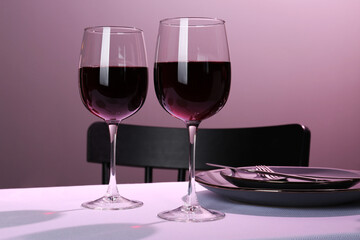 Romantic table setting with glasses of red wine indoors