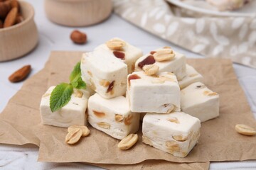 Pieces of delicious nutty nougat on parchment paper, closeup