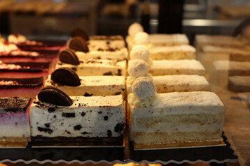 Different delicious cakes on counter in bakery shop, closeup