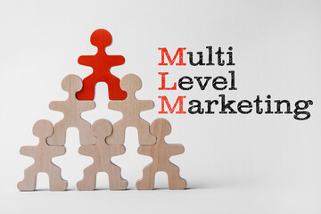 Multi-level marketing. Pyramid of wooden human figures with red one at top showing hierarchy on...