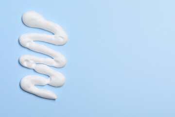 Sample of shaving foam on light blue background, top view. Space for text