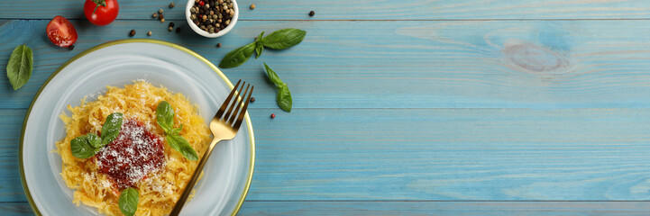 Tasty spaghetti squash with tomato sauce, cheese and basil served on light blue wooden table, flat lay. Banner design with space for text