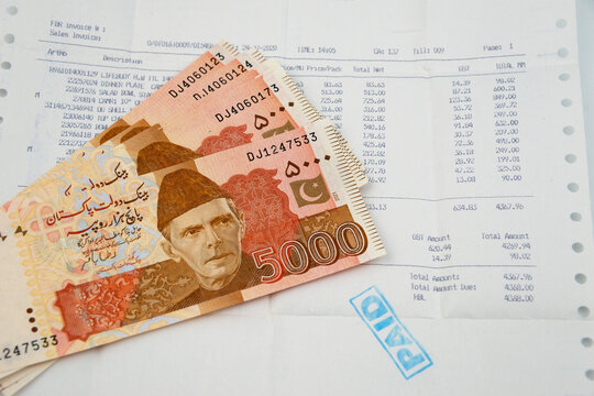 Currency notes in Pakistani Rupees with a paid invoice.