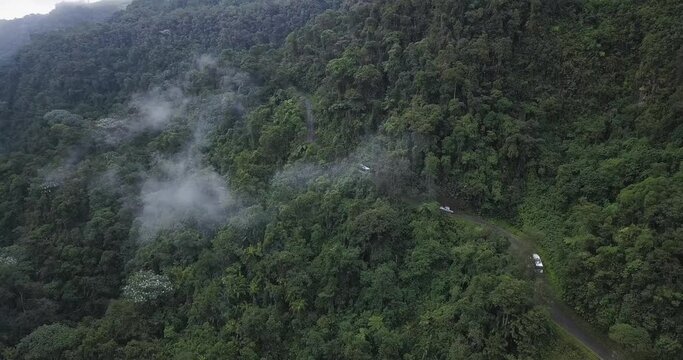 Drone shot of buses riding through treacherous road in the jungles of Colombia