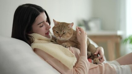 Beautiful woman spends her free time on vacation playing with her cute cat at home.