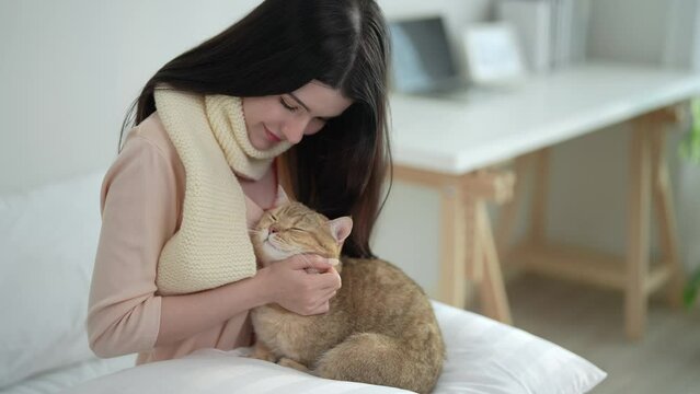 Beautiful woman spends her free time on vacation playing with her cute cat at home.