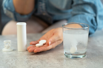 Female hands with pills on background of water glass with effervescent tablet. Soluble drug.Take...