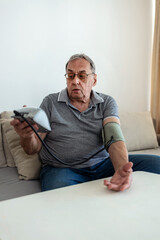Man sitting checking blood pressure at home.