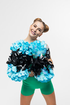 Portrait of an attractive cheerleader in a green suit on a white background. Pom-poms in your hands