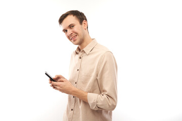 Portrait of young handsome caucasian man using mobile phone and smiling isolated on white studio background, joyful facial expression
