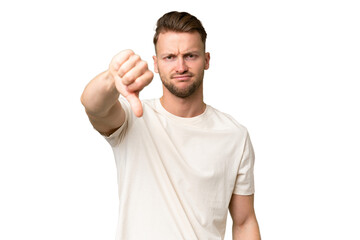 Young blonde caucasian man over isolated background showing thumb down with negative expression