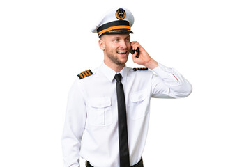 Airplane pilot man over isolated background keeping a conversation with the mobile phone