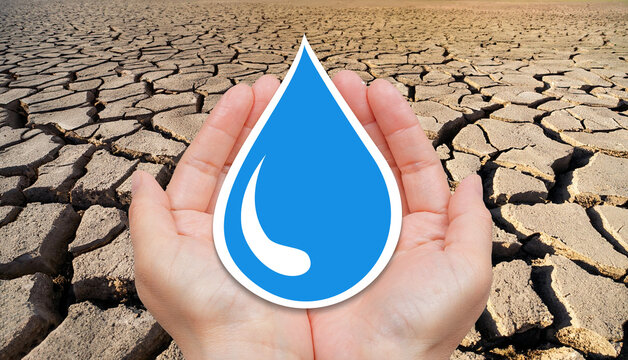 Water conservation concept with dry and cracked soil background. Human hands holding blue water drop.