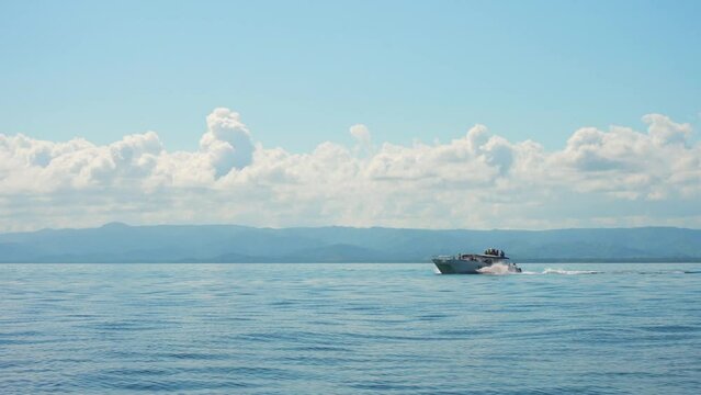 Speed motor boat with tourists on board floating fast on calm blue water surface. 