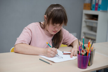 Sunny girl painting in art class at school. World day of people with down syndrome