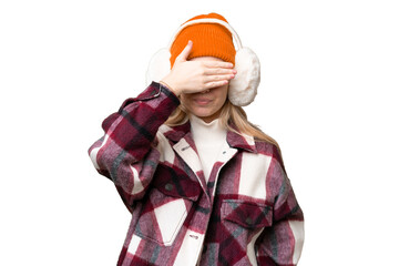 Young  English woman wearing winter muffs over isolated background covering eyes by hands. Do not want to see something