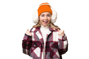 Young  English woman wearing winter muffs over isolated background celebrating a victory in winner position