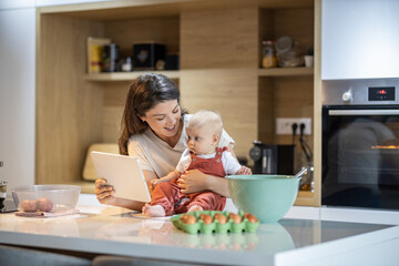 Mom plays her baby a cartoon as she holds her on the kitchen counter