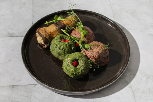 Mix of georgian phali or pkhali with beetroot, spinach, and aubergine on black plate