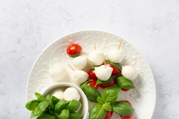 Mozzarella cheese balls, tomatoes, basil leaves and peppercorns for caprese salad flying on white background.