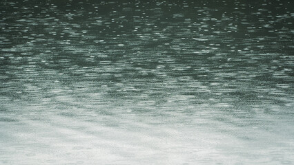 Raindrops on water surface. Raindrops falling on teal colored water. Minimal background.