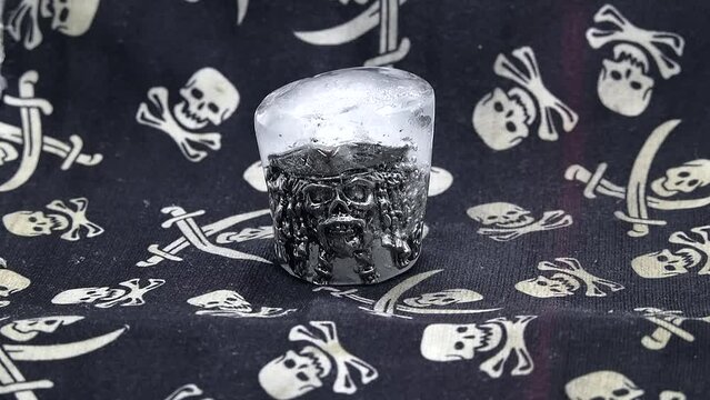 A ring in the shape of a pirate's skull in a hat and beard is thawed out of ice in a video time-lapse