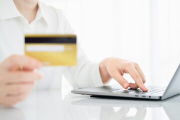 Woman hand holding credit card and using laptop at home, online shopping and paying bills, Payment method.