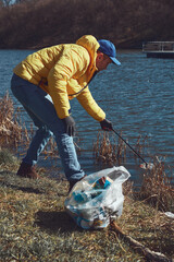 Volunteer and environmental activist cleaning dirty lake shore filled with trash.