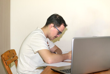 Young man with glasses studying concentrated at his desk with his computer