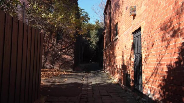 A cobblestone pedestrian-only laneway between old classic red brick house in the afternoon sunlight. The suburb of Northcote, Melbourne VIC Australia. 