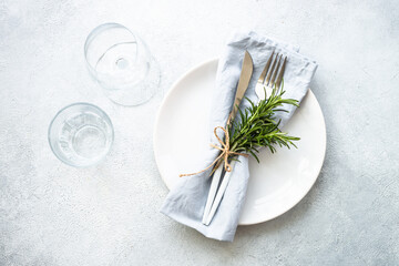 White plate, shaker, wine glass and cutlery on stone table. Table setting, flat lay image with copy...